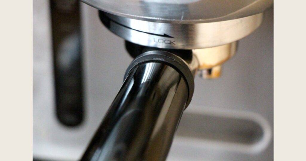Close-up of a portafilter handle locked into an espresso machine group head.