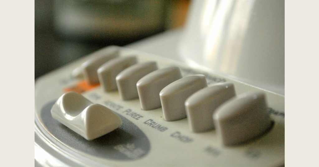 Rows of rectangular buttons on a pale appliance control panel.